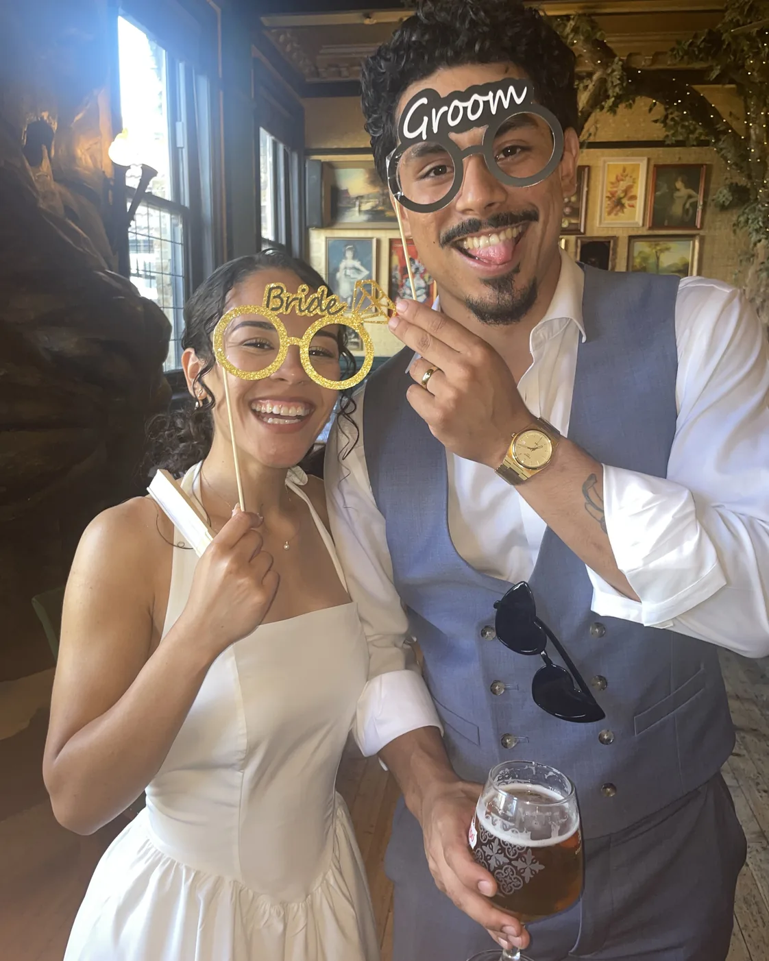 Newlyweds posing together with playful wedding glasses