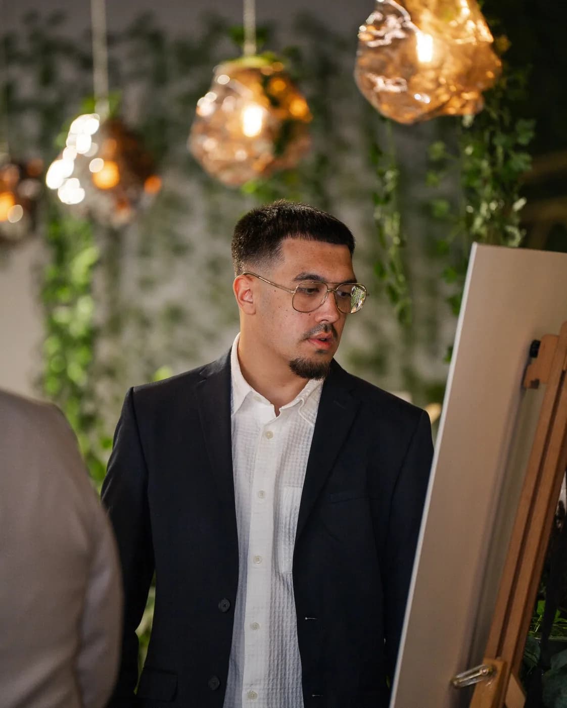 A guest reading a seating plan beneath warm pendant lights