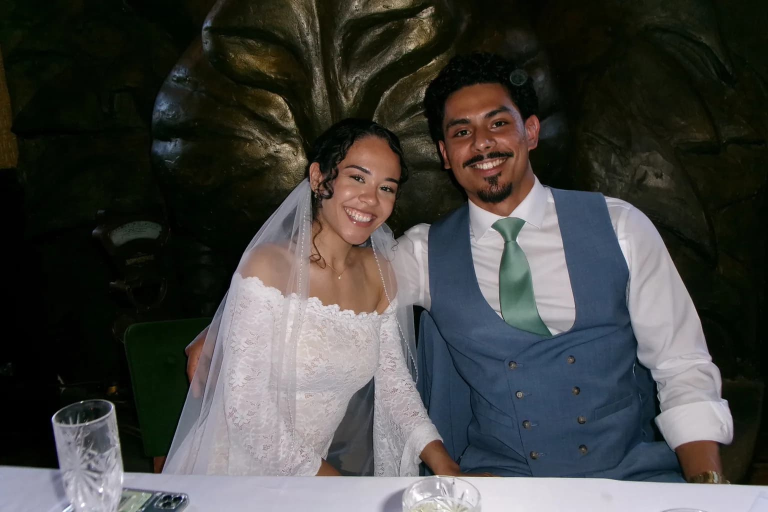 Newlyweds smiling together at their reception table